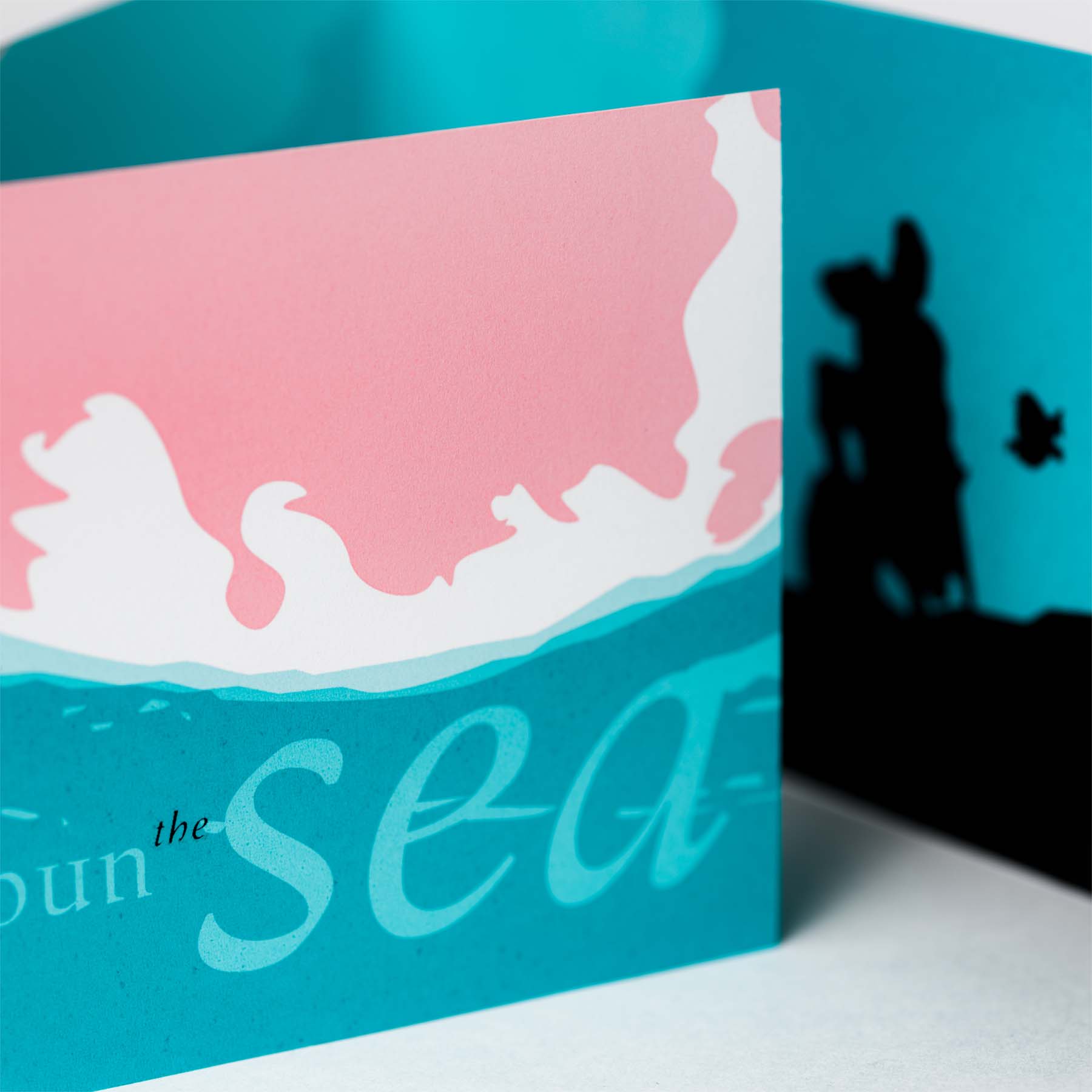 Detail of partially opend trifold card, featuring sunked statue of Prince Erik from the 'Little Mermaid'.